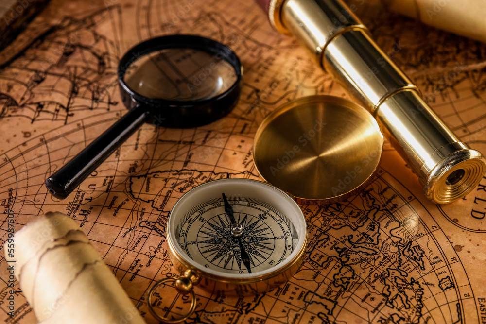 Golden compass, magnifier and spyglass on world map