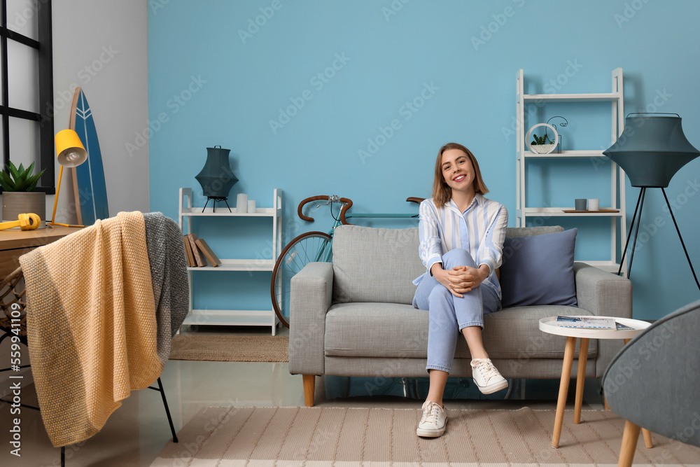 Young woman sitting on grey couch in living room