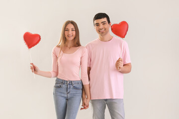 Sticker - Young couple in love with balloons on light background. Valentine's Day celebration