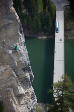 Man Climbs Cliff Above Highway Bridge With Cars
