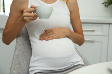 Canvas Print - Beautiful pregnant woman drinking tea in kitchen, closeup