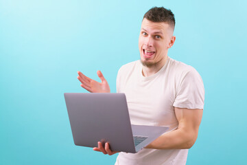 Happy surprised caucasian man holding laptop and looking at camera on a blue backgorund. Emotional. Smiling. Studio. White. Laugh. Laughing. Successful. Occupation. Media. Express. Working. Work