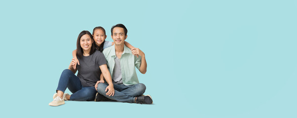 Wall Mural - Happy smiling young asian family sitting on floor and have a fun time together, Full body isolated on pastel plain light blue background