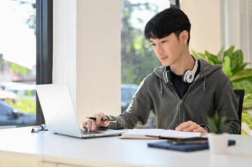 Smart young Asian male college student doing his school homework