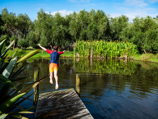  A boy is jumping into a natural pond during summer