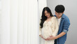 married couple is expecting baby. man embraces his pregnant wife on window background