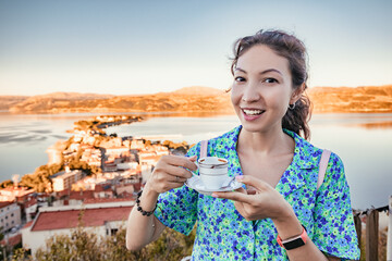 Wall Mural - Happy asian girl drinks traditional and authentic Turkish strong coffee in the resort town cafe