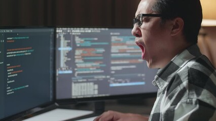 Close Up Of Asian Male Programmer Yawning While Creating Innovative Software Engineer Developing App, Program, Video Game On Desktop Computer At Home. Terminal With Coding Language 
