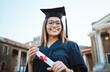 Portrait, graduate and study with a student woman holding a diploma or certificate outdoor on graduation day. Education, goal or unviersity with a female pupil outside after scholarship success