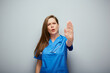 Stop gesture. Doctor woman or nurse in blue medical suit showing palm forward.