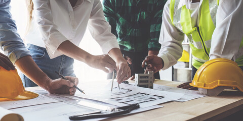 Architect team working with blueprints for architectural plan, engineer sketching a construction project, green energy concept