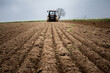 Un agriculteur dans son tracteur sème un champ d'orge.