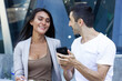 © Josu Ozkaritz - Caucasian man showing viral video on phone to Asian woman colleague in urban city. Multiracial teamwork funny business talk, startup project ideas, modern technology concepts