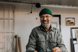 © Maskot - Portrait of cheerful male owner wearing knit hat and eyeglasses in workshop