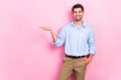 Photo of joyful cheerful man arm demonstrate empty space cool proposition vacancy isolated on pink color background