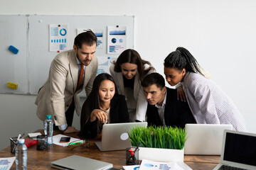 a team of developers is committed to a project while looking at a laptop monitor together