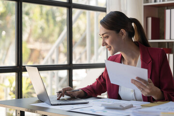 Smile Pretty business Asian woman is working her job on a laptop computer in a modern office. Doing accounting analysis report real estate investment data, Financial and tax systems concept