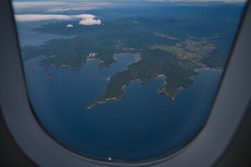 Aerial landscape view of islands and blue beautiful sea from the window in the airplane