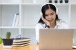 © Wasan - Asian woman working with laptop while having online conference at home office.