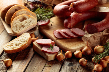 Wall Mural - On a old wooden table sausage with bread, rosemary, onion and pepper.