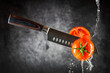 Messer schneidet durch frische Tomate und Wasser läuft runter.