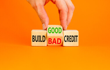 Wall Mural - Build good or bad credit symbol. Concept word Build good or bad credit on wooden cubes. Businessman hand. Beautiful orange table orange background. Business build good bad credit concept. Copy space