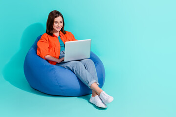 Sticker - Full length photo of positive girl dressed shirt bean bag writing message device empty space isolated turquoise color background