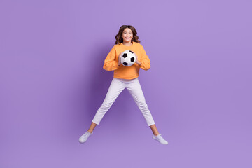 Sticker - Full body portrait of cheerful carefree girl jumping hands hold football isolated on purple color background