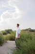 © Maxim - a man in a white shirt stands on the sand dunes looks up to the sky, looks thoughtfully up