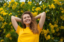 Portrait Of Happy Beautiful Bearded Girl, Young Positive Woman With Beard Is Smelling Beautiful Yellow Flowers In The Garden, Smiling, Enjoying Spring Or Summer Day, Breathing Deep Deeply Fresh Air