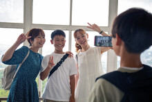 A Boy Using His Mobile Phone To Take A Picture Of Three Japanese People, A 13 Year Old Boy, His Mother And A Friend.