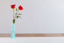 An Isolated Small Turquoise Glass Vase With Two Beautiful Red Roses With Copy Space.