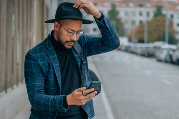 latin man with hat looking at mobile phone in the street