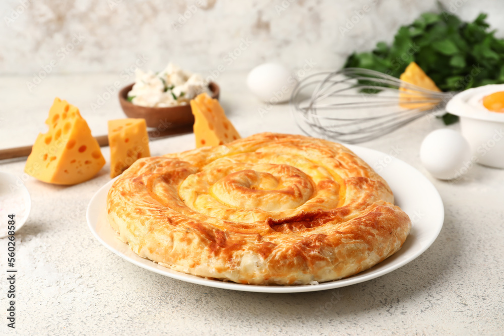 Plate with delicious cheese pie and ingredients on white table