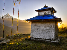 A Little Religious Shrine Building Sits On A Grassy Terrace In Front Of A Mountain In The Annapurna Region Of Nepal.
