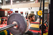 © Cavan Images - side view of man completing squats at the gym