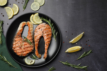 Plate with tasty salmon steaks on black table, flat lay. Space for text