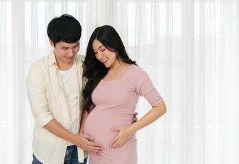 Wall Mural - married couple is expecting baby. man embraces his pregnant wife on window background