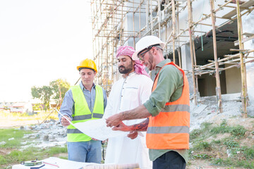 Wall Mural - Diverse team of professionals using tablet computers on construction site. Real estate construction project. with civil engineers, architects, Arabic business investors and explorer with theodolite