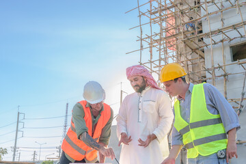 Wall Mural - Diverse team of professionals using tablet computers on construction site. Real estate construction project. with civil engineers, architects, Arabic business investors and explorer with theodolite