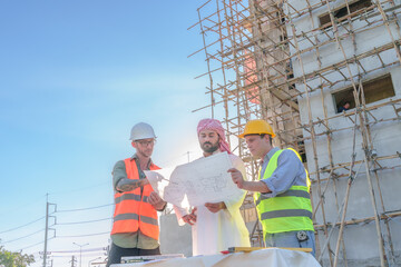 Wall Mural - Diverse team of professionals using tablet computers on construction site. Real estate construction project. with civil engineers, architects, Arabic business investors and explorer with theodolite