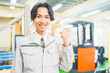 © HML - 作業服を着て倉庫でガッツポーズをする若いビジネスマン