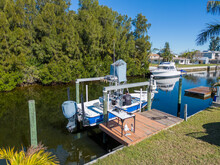 Tower Boat With Covers On Boat Lift With Deck Dock With Person On Board In Tampa Florida From Aerial Drone