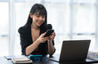 © crizzystudio - Asian businesswoman in formal suit in office happy and cheerful during using smartphone and working
