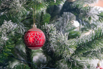 Close up of red bauble hanging from Christmas tree.