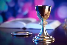 Religion Theme. Religion Symbols Composition. The Cross, Monstrance,  Holy Bible, Rosary And Golden Chalice On Blue Bokeh Background. 