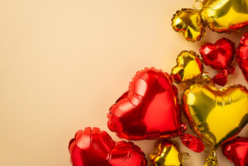 Wall Mural - Valentine's Day concept. Top view photo of heart shaped red and yellow balloons on isolated pastel beige background with copyspace