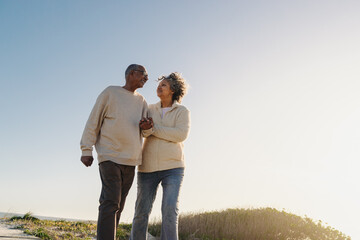 Wall Mural - Low angle view of a senior couple walking down a foot bridge at the beach