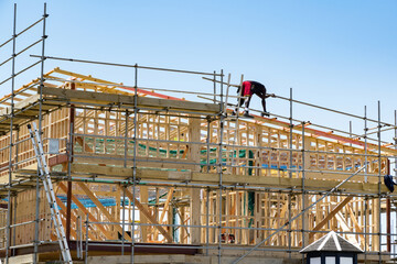 Construction site with wooden frame and worker on roof