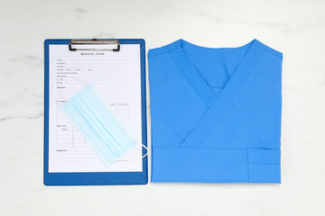 Poster - Medical uniform and clipboard on white marble table, flat lay